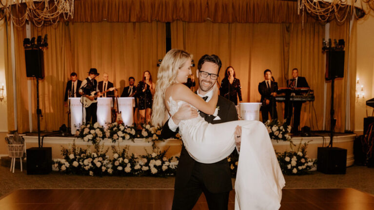 A bride and groom share a joyful moment on the dance floor with a 20-piece wedding band from Ben Mallare Events & Entertainment performing live in the background, creating an unforgettable wedding reception atmosphere.
