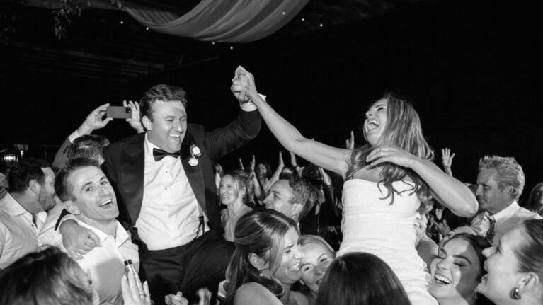 A lively wedding celebration featuring a groom being lifted by friends, surrounded by joyful guests dancing together. This vibrant scene captures the energy of a live wedding band performance, highlighting the unforgettable moments created by Ben Mallare Events & Entertainment. The excitement in the air showcases how a professional wedding band enhances the atmosphere, ensuring an unforgettable experience for everyone involved.
