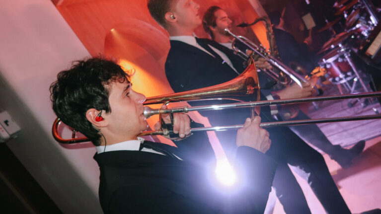 Kelly & Skyler A dynamic performance by a talented 20-piece wedding band, featuring musicians playing brass instruments on stage. This image captures the energy and excitement of live wedding entertainment, showcasing the vibrant atmosphere created by Ben Mallare Events & Entertainment. Perfect for couples looking to elevate their wedding with unforgettable live music.