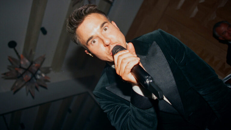 Kelly & Skyler Film A charismatic male vocalist performing live, capturing the energy of a wedding celebration with a 20-piece wedding band. This image showcases the vibrant atmosphere created by live wedding bands, perfect for couples seeking exceptional entertainment for their special day. Ben Mallare Events & Entertainment specializes in providing unforgettable musical experiences that enhance wedding receptions.