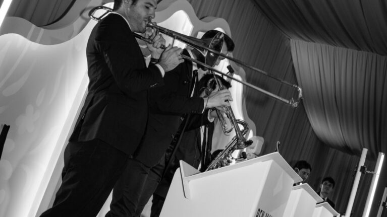 Jane & David Wedding Gallery A talented musician playing the trombone as part of a live wedding band performance, showcasing the vibrant energy and entertainment options provided by Ben Mallare Events & Entertainment. This dynamic scene highlights the sophistication of a 20-piece wedding band, ideal for creating memorable moments at weddings and special events. The elegant setting enhances the overall atmosphere, making it a perfect choice for couples seeking live music to elevate their celebration.