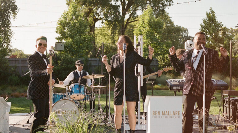 Hannah + Gary A dynamic 7-piece wedding band performing at an outdoor Napa Valley event, showcasing talented musicians and vocalists engaging the audience with lively music. Ben Mallare Events & Entertainment provides exceptional Napa Valley Live Wedding Bands Music Entertainment, creating unforgettable moments for couples on their special day.